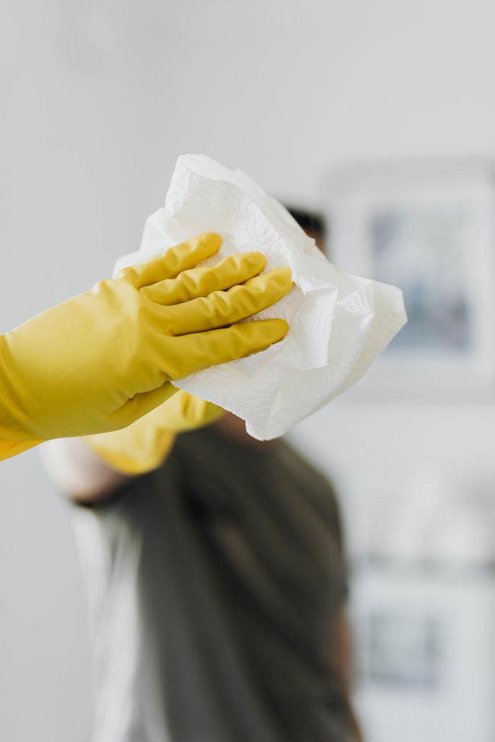 services-05 Anonymous male wearing yellow latex gloves and dark t shirt wiping mirror in bathroom with paper napkin